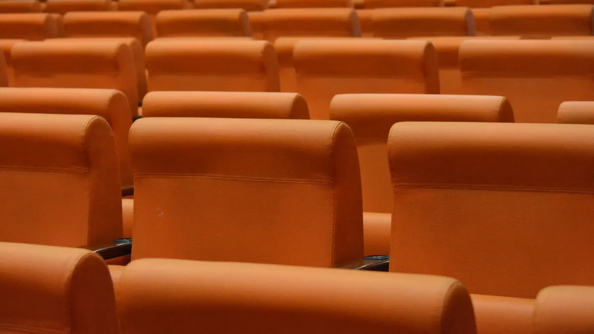 Rangées de sièges orange en cuir dans un auditorium intérieur